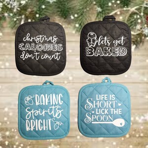 May include: Four black and blue quilted pot holders with white text. The black pot holders have the text "christmas calories don't count" and "let's get baked". The blue pot holders have the text "baking spirits bright" and "life is short lick the spoon".