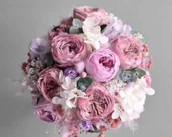 May include: A bouquet of pink and white roses, hydrangeas, and other flowers. The bouquet is arranged in a circular shape and is tied with a ribbon.