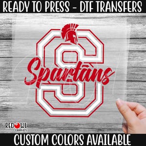 May include: Red and white iron-on transfer design featuring a Spartan helmet and the word "Spartans".  Ready to press DTF transfer.