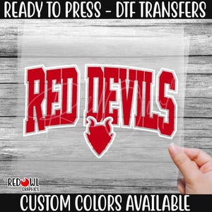 May include: Red Devils iron-on transfer design. The design features the words "Red Devils" in a bold, red font with a red devil silhouette. The design is ready to press onto fabric.