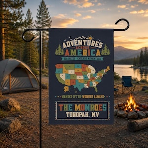 Może przedstawiać: Granatowa flaga ogrodowa z napisem "ADVENTURES ACROSS AMERICA" i mapą Stanów Zjednoczonych. Flaga zawiera również napis "THE MONROES TONOPAH, NV". Flaga jest wyświetlana na zewnątrz.