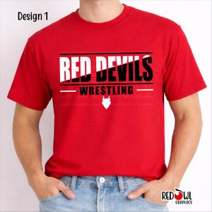 May include: A red t-shirt with the text "RED DEVILS WRESTLING" in white and black. The shirt also features a white devil head graphic. The design is labeled "Design 1" in the upper left corner.