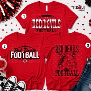 May include: Three red t-shirts featuring football-themed graphics. The top shirt displays "RED DEVILS FOOTBALL" with a football icon. The bottom left shirt shows "Red Devils FOOTBALL" with a football. The bottom right shirt features a helmet graphic.