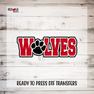 May include: A graphic design featuring the word WOLVES in bold red block letters with a black outline. The letter O is replaced by a solid black paw print. The text RED OWL GRAPHICS appears in the top left corner and READY TO PRESS DTF TRANSFERS at the bottom.