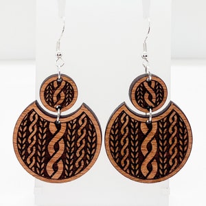 May include: A pair of wooden earrings with a geometric pattern. The earrings are brown and have a silver hook.