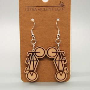 May include: A pair of wooden earrings with a geometric design, featuring a diamond shape and circles. The earrings are on a brown card with the text "Ultra Violent Light".