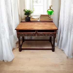 May include: A dark wood console table with two drawers and carved details. The table has a simple design with turned legs and a rectangular top.