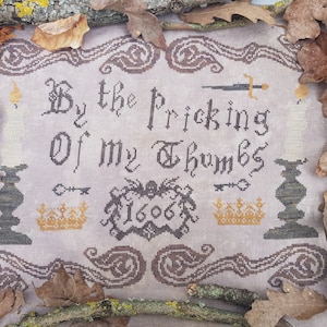 May include: Cross-stitch embroidery on linen fabric with the text "By the Pricking of my Thumbs 1606" surrounded by a decorative border and candlesticks.
