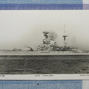 May include: A black and white photograph of a large warship, the HMS Ramillies, sailing on the water. The ship has a tall mast and several gun turrets. The photo is captioned "HMS Ramillies" and "Alastair Denigro".