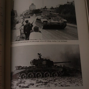 K&ouml;nnte beinhalten: Ein Schwarzwei&szlig;foto eines britischen Comet-Panzers, der &uuml;ber ein Feld f&auml;hrt. Der Panzer feuert seine Hauptkanone ab. Das Foto stammt aus dem Tank Museum.