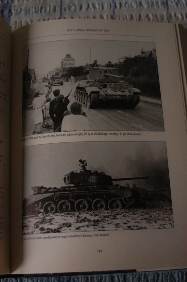 K&ouml;nnte beinhalten: Ein Schwarzwei&szlig;foto eines britischen Comet-Panzers, der &uuml;ber ein Feld f&auml;hrt. Der Panzer feuert seine Hauptkanone ab. Das Foto stammt aus dem Tank Museum.