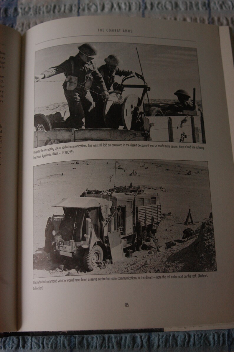 K&ouml;nnte beinhalten: Ein Schwarzwei&szlig;foto eines Milit&auml;rfahrzeugs in der W&uuml;ste. Das Fahrzeug hat eine Funkantenne auf dem Dach und ist von Sand umgeben. Der Text "Despite the increasing use of radio communications, line was still laid on occasions in the desert because it was so much more secure. Here a land line is being laid near Agedabia. (IWM - E 20899)" ist unter dem Bild gedruckt.