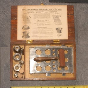 May include: A wooden box containing a metal tray and various tools for closing machines. The box lid features a printed paper insert with the text "PRICES OF CLOSING MACHINES HOW TO USE THEM CYGNET," "CHRISTY" and KOSEALS."