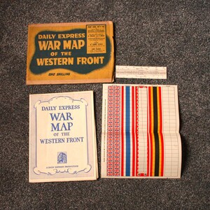 May include: A collection of vintage World War I maps and related items. The image shows a map titled "Daily Express War Map of the Western Front" and a slide rule. The map has a yellow and green cover.