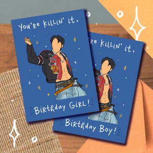 May include: Two blue birthday cards featuring illustrations of a person in a jacket and jeans. The cards read "You're killin' it," with "Birthday Girl!" and "Birthday Boy!" below the illustrations. The background is blue with star accents.
