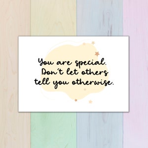 Puede incluir: Una tarjeta blanca con una forma abstracta amarilla y dorada y estrellas doradas. La tarjeta tiene el texto "You are special. Don't let others tell you otherwise."