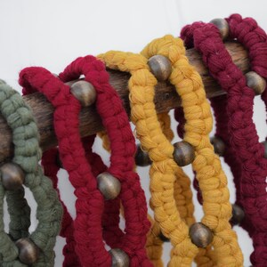 May include: Four braided rope bracelets with wooden beads in shades of green, red, and yellow.