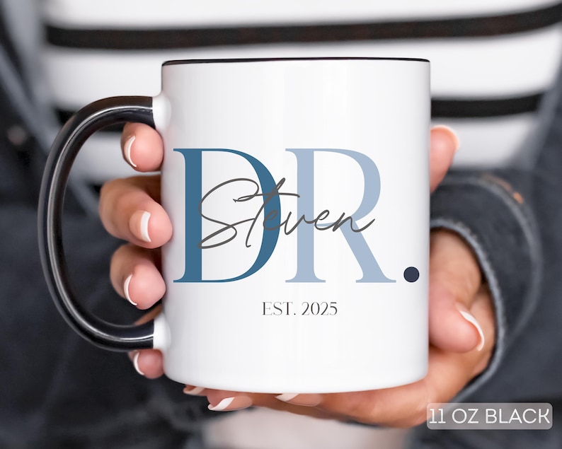 May include: White ceramic mug with a black handle and rim, featuring the text "DR. Steven" in blue and gray, with "EST. 2025" below. The mug is labeled "11 OZ BLACK".