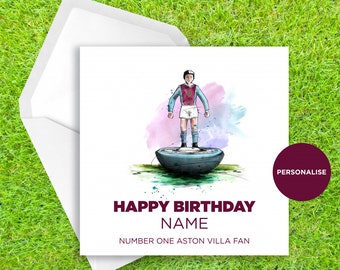 May include: A birthday card featuring a watercolor illustration of a cartoon figure wearing a blue and maroon soccer jersey standing on a soccer ball. The card says "Happy Birthday NAME Number One Aston Villa Fan".