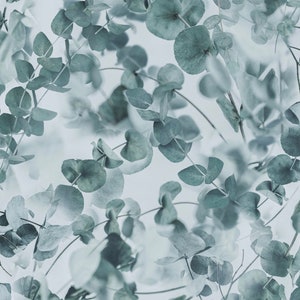 以下が含まれることがあります： 薄い青色の背景にユーカリの葉が繰り返しデザインされたシームレスなパターン。葉はランダムなパターンで配置され、わずかにぼやけており、柔らかく幻想的な効果を生み出しています。