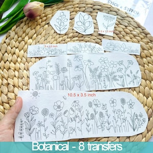 Peut inclure: Huit motifs de broderie imprimables représentant des motifs floraux. Les motifs sont imprimés sur du papier blanc et comprennent une variété de fleurs, de feuilles et de tiges. Le motif le plus grand mesure 10,5 pouces par 3,5 pouces. Le texte "Botanical - 8 transfers" est imprimé en bas de l'image.