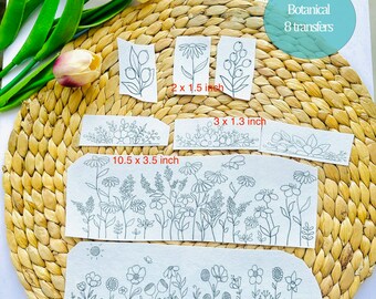 May include: Eight botanical embroidery transfer designs on white fabric. The designs include a variety of flowers, leaves, and stems. The transfers are labeled with their size in inches.  "Stick & Stitch Embroidery Designs" and "Botanical 8 transfers" are printed on the top of the image.