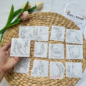 May include: A set of 12 embroidery designs featuring floral letters of the alphabet. Each design is 2.5 inches by 2.5 inches. The designs are printed on white paper and are ready to be stitched.
