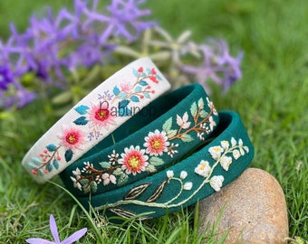 May include: Three embroidered headbands with floral designs. The headbands are white and green. The floral designs are pink, white, and green.