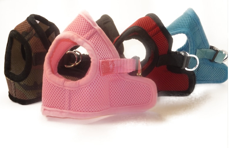 Pu&ograve; includere: Quattro diversi tipi di pettorine per cani di diversi colori con tessuto a rete e cinturini regolabili. Le pettorine sono in mimetico, rosa, rosso e blu.