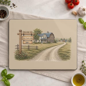 May include: A rectangular glass cutting board featuring a printed illustration of a rural farmhouse and a dirt road. A wooden signpost in the foreground displays the text WELCOME TO, YOUR TOWN, USA, and ZIP--. The scene includes a barn and trees.