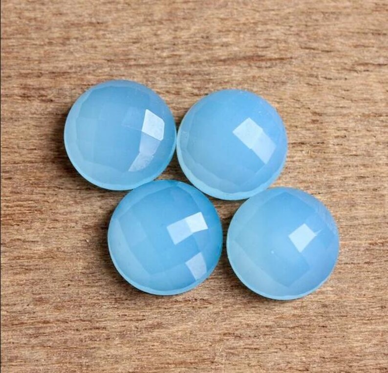 May include: Four light blue round cabochon gemstones with a faceted finish.