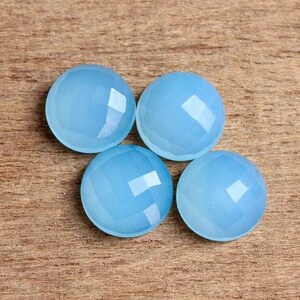 May include: Four light blue round cabochon gemstones with a faceted finish.