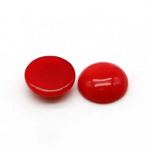 May include: Two red round cabochon glass gems. The gems are smooth and shiny.