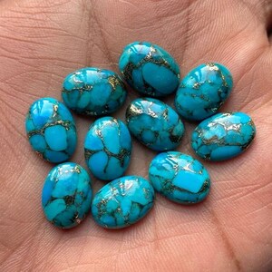 May include: Ten oval-shaped turquoise cabochons with silver veins. The stones are a vibrant blue-green colour and have a smooth, polished finish.