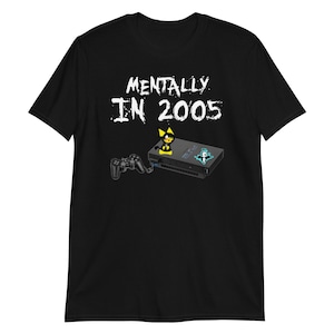May include: Black t-shirt with the text "MENTALLY IN 2005" in white. A graphic of a black PlayStation 2 console, a controller, and a cartoon character are featured below the text. The shirt is a short-sleeve style.