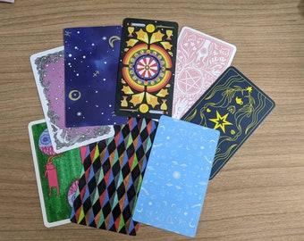 May include: A set of ten tarot cards with colorful illustrations and designs. The cards feature a variety of symbols and imagery, including stars, a wheel, a pentagram, and a creature with a single eye. The cards are printed on thick cardstock and have a matte finish.