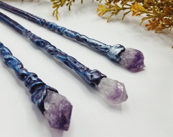 Puede incluir: Tres varitas con puntas de cristal de amatista. Las varitas son azules y moradas con un diseño retorcido.