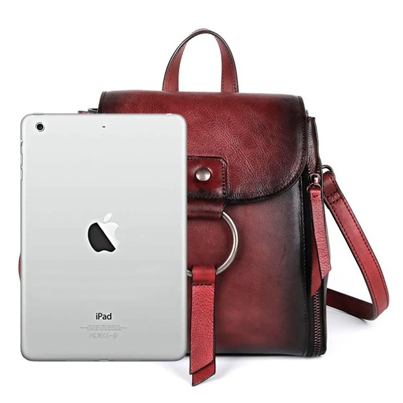 Stylish handmade women's leather backpack in rich burgundy, featuring a spacious design perfect for securing an iPad, showcased with a modern tablet for scale, blending elegance and practicality for the discerning buyer