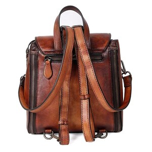 Rear view of a handcrafted, high-quality women's leather backpack with adjustable straps, multiple zipper compartments, and fine stitch detailing, in a rich two-tone brown color.
