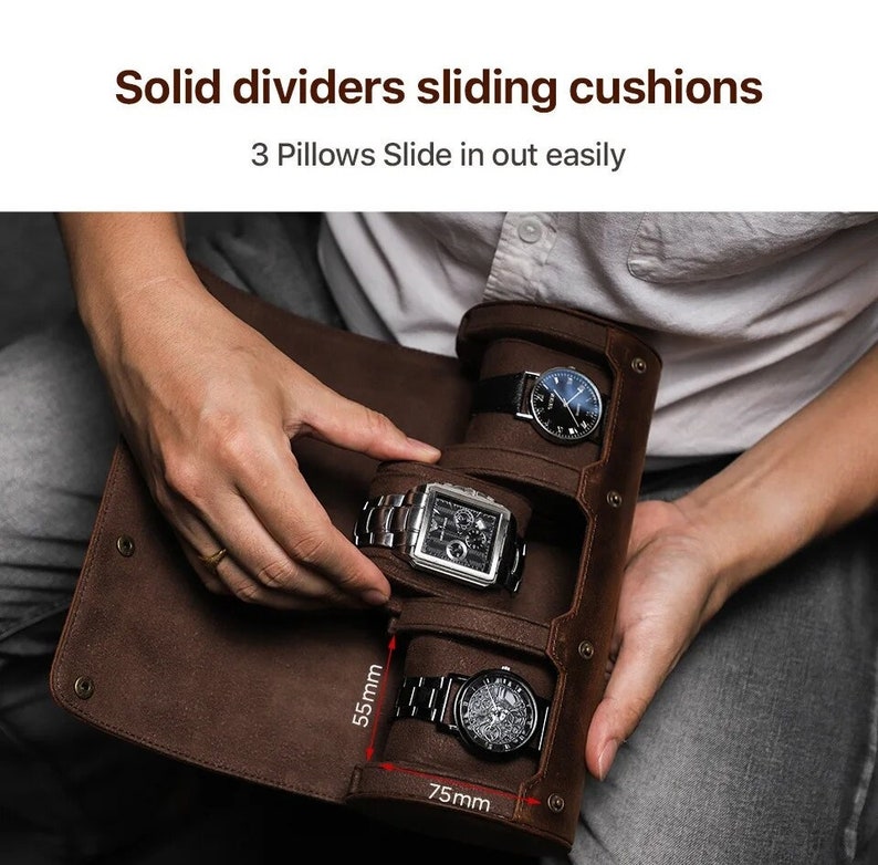 May include: A brown leather watch roll with three compartments, each holding a wristwatch. The roll is open, revealing the watches. Text at the top reads "Solid dividers sliding cushions" and "3 Pillows Slide in out easily". The roll measures 75mm wide and 55mm high.