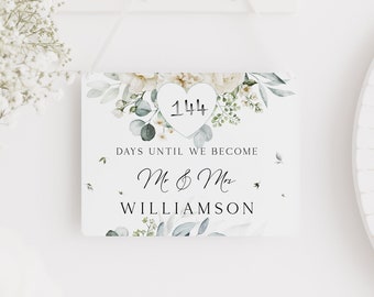 May include: White wedding countdown sign with floral design and the text "144 Days Until We Become Mr & Mrs Williamson"