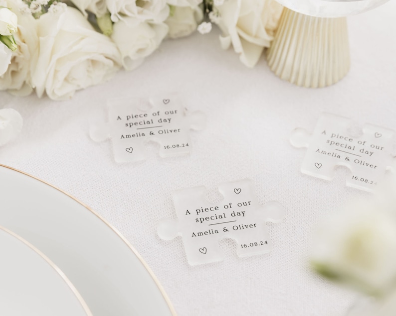 May include: Three clear acrylic puzzle pieces with the text "A piece of our special day Amelia & Oliver 16.08.24" printed on each piece.