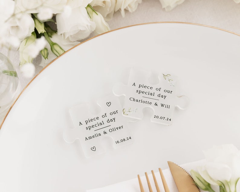 May include: Two clear acrylic puzzle pieces with the text "A piece of our special day" and the names of the couples, "Amelia & Oliver" and "Charlotte & Will", along with their wedding dates.