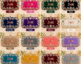 Puede incluir: Una colección de bolsos de mano rectangulares de terciopelo en dieciséis colores diferentes, cada uno con las letras S y M bordadas en oro separadas por un corazón rojo, rodeadas por un borde decorativo de bordados florales y cristales.