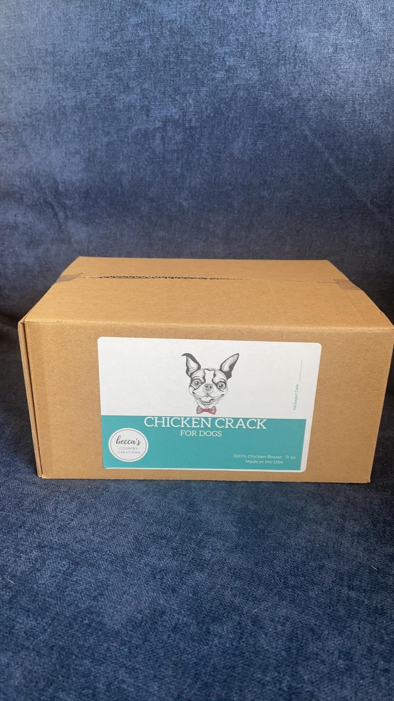Puede incluir: Una caja de cart&oacute;n marr&oacute;n con una etiqueta que dice "Chicken Crack for Dogs". La etiqueta presenta una ilustraci&oacute;n en blanco y negro de un perro. La caja contiene 312 gramos de pechuga de pollo.