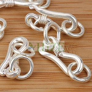 May include: Silver-toned metal clasps with a looped design. The clasps are designed to connect two pieces of jewelry or other items.