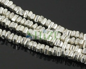 May include: A strand of silver-toned metal beads, each bead is a hexagonal shape with a slightly irregular, hammered finish.