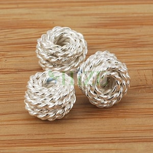 May include: Three silver-toned metal beads with a rope-like design. The beads are round and have a hole in the centre.