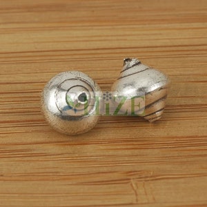 May include: Two silver metal beads, one round and one with a spiral design.