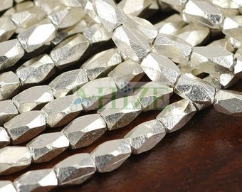 May include: A strand of silver-toned faceted beads. The beads are hexagonal in shape and have a hammered texture.